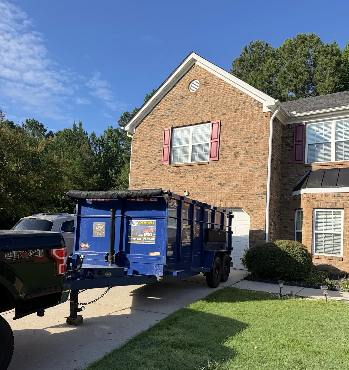 TPM Trailers blue 20-yard dump trailer positioned safely in a residential driveway near Atlanta