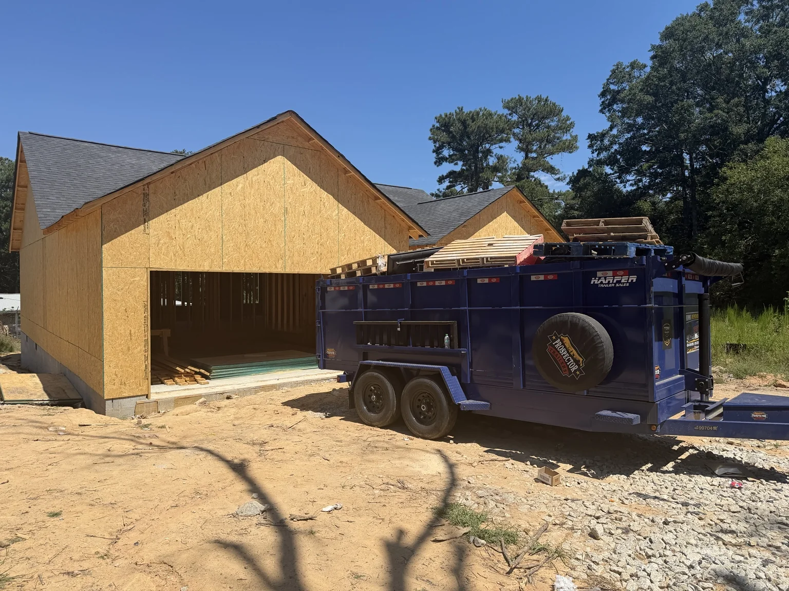 TPM Trailers blue dump trailer beside a framed new-construction home in Georgia